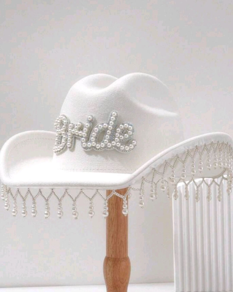 A white cowboy hat with Bride spelt out in rhinestones and a fringe of crystals