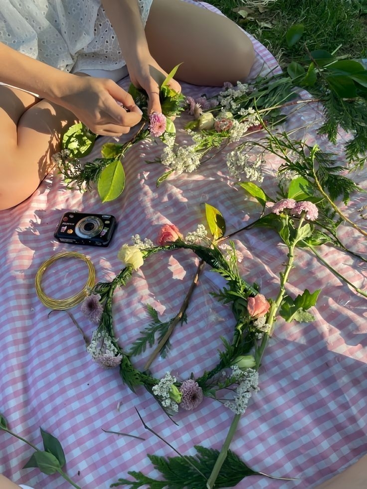 Flower crowns and a camera laid out on a gingham picnic blanket