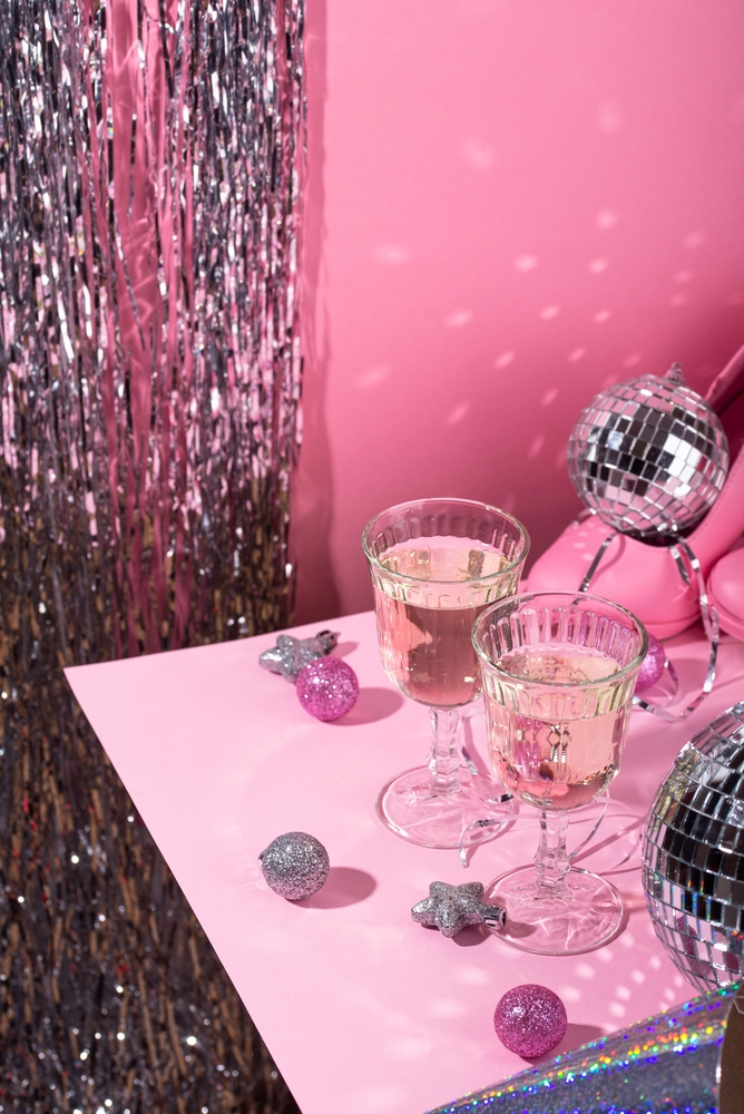 A pink tinsel curtain behind a table of coupes and small mirror balls