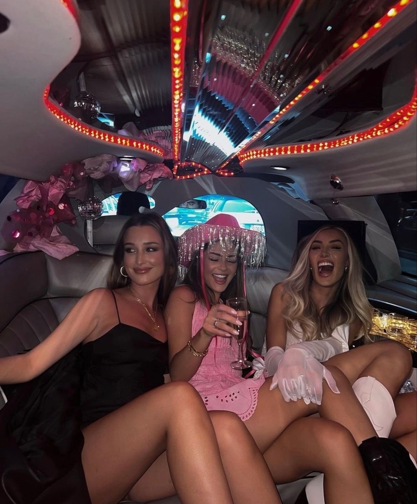 Four friends in party wear laughing together inside a limo