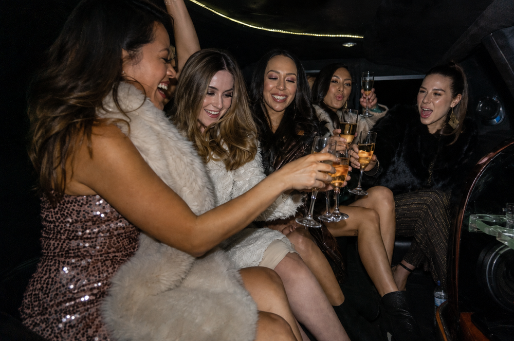 A group of women toasting inside a limo at night