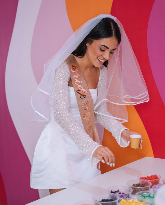 A bride to be in a veil and sash at a colourful table