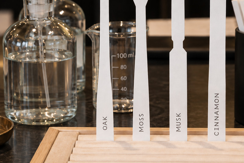Glass perfume bottles beside scent strips labelled oak, moss, musk and cinnamon at a perfume making class