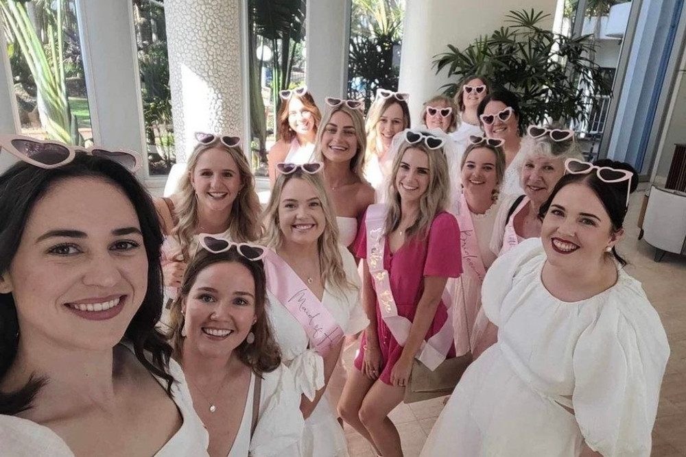 A big hens group in white and pink squeezing into a sunny selfie on a terrace