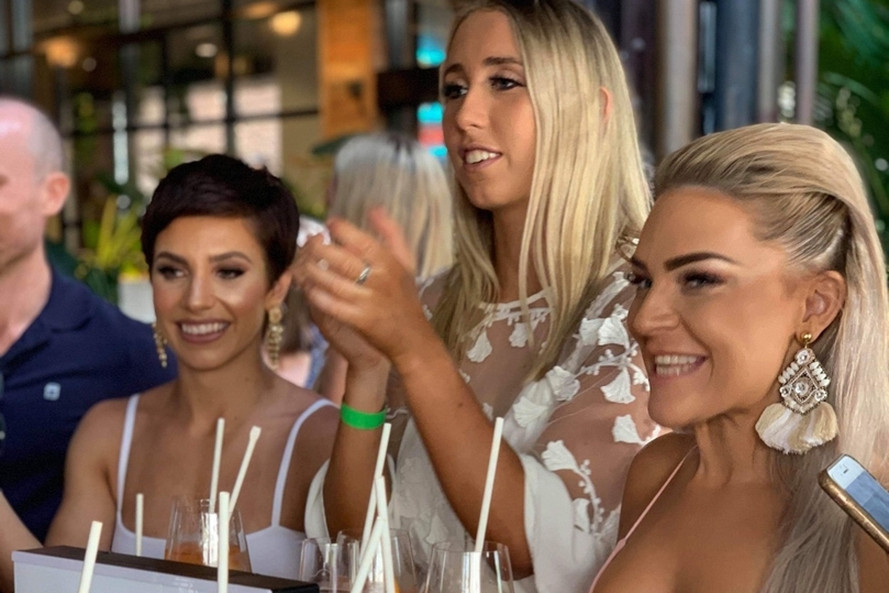 Four friends laughing around a table of orange spritzes
