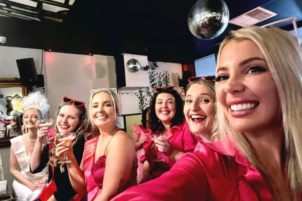 Friends in pink crowding into a laughing selfie under a disco ball