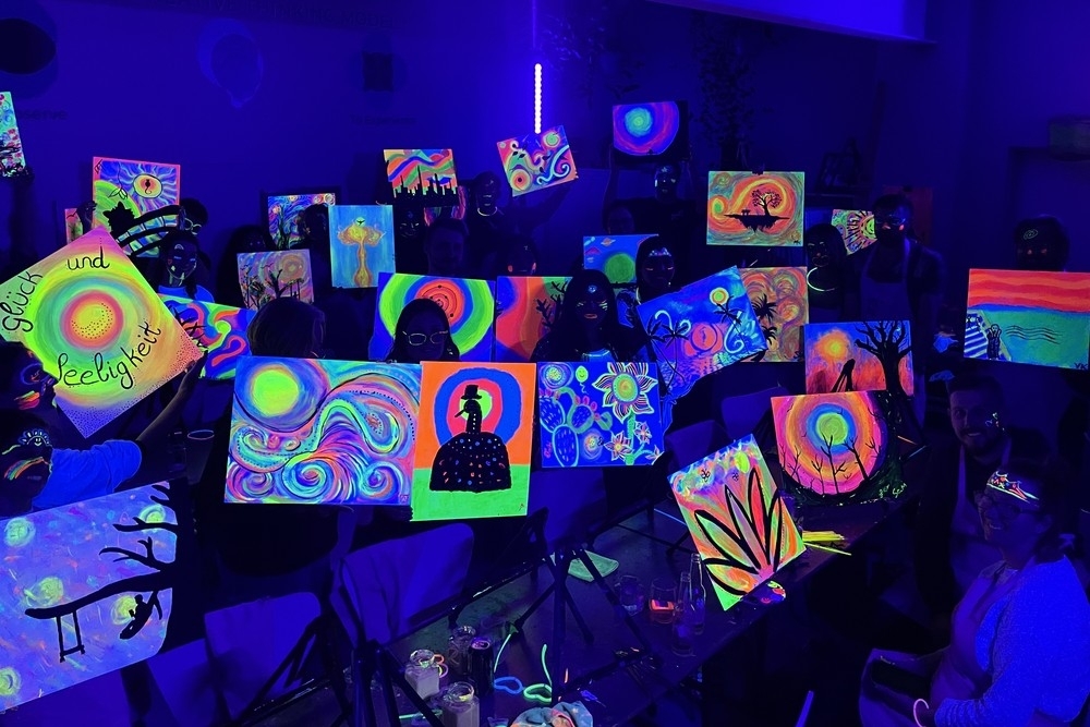 Canvases glowing bright under UV light, held up in a dark room