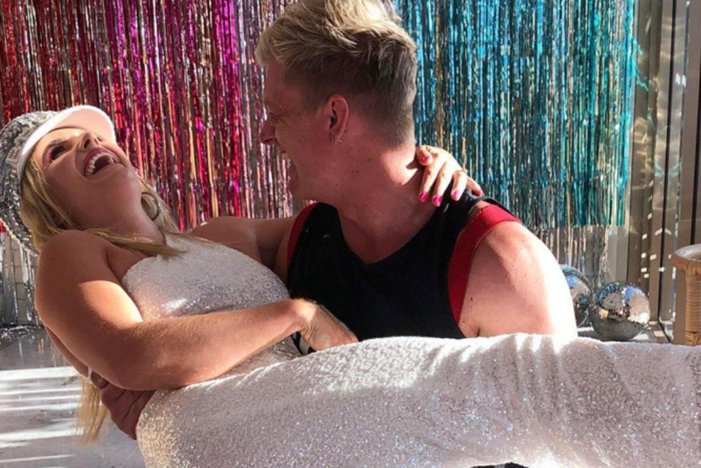 A fireman carrying the laughing bride to be in front of a tinsel curtain