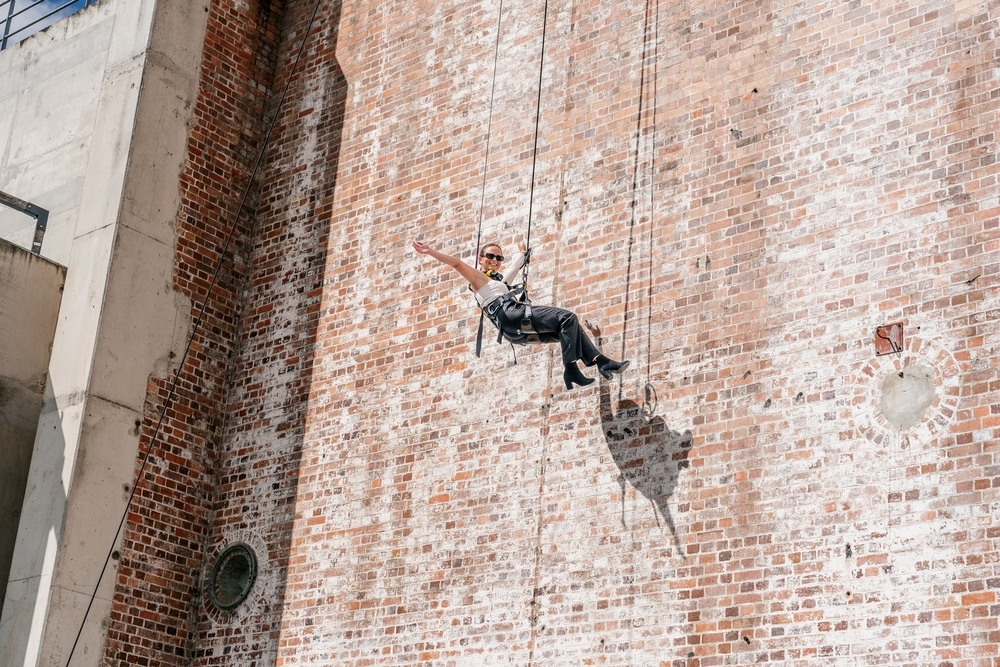 A person abseiling down a brick building wall