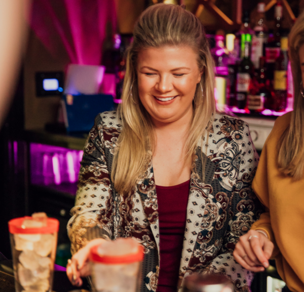 A hen laughing as she makes a cocktail behind the bar