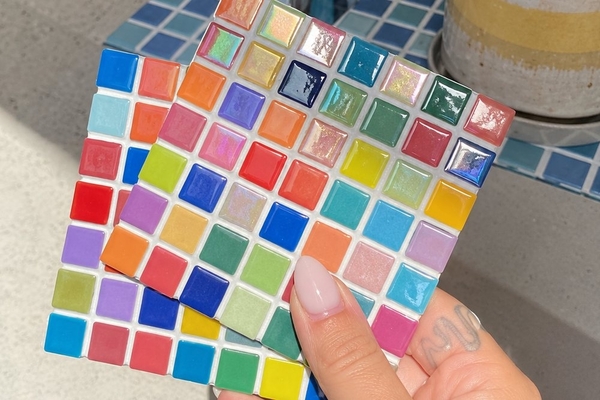 Two finished rainbow glass tile mosaics held up in the sunshine