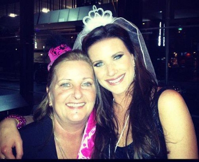 The bride in a veil and tiara, cheek to cheek with a friend at her burlesque hens