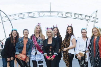 A hens group in horned headbands under the Surfers Paradise sign arch